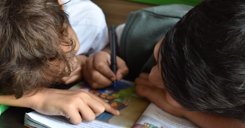 two school-aged boys reading a book together