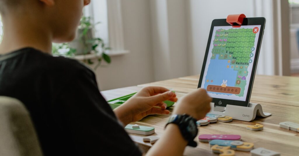 school aged boy playing a game on ipad with puzzle peices on the table